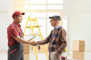 Mover shaking hands with a senior man in a house